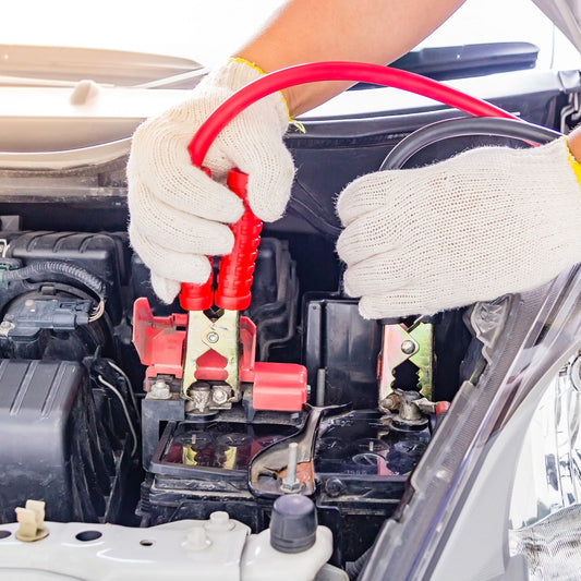 A technician connects jumper cables to a car battery during a roadside assistance jump start in Toronto, Ontario.